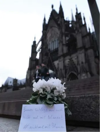  ?? ROBERTO PFEIL/AFP/GETTY IMAGES ?? Flowers and a letter reading “One doesn’t beat women — not even with flowers” are laid down in front of Cologne’s landmark, the Cologne Cathedral, near the main railway station on Thursday to commemorat­e victims of the apparently co-ordinated sex...