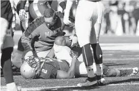  ?? PAUL W. GILLESPIE/BALTIMORE SUN MEDIA GROUP ?? A trainer tends to Toneo Gulley after the Navy co-captain was injured in the second quarter of the Mids’ loss to Temple. Navy announced that Gulley is out for the season.