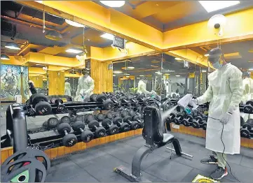  ?? SANJEEV VERMA/HT PHOTO ?? A staffer sanitises equipment at a gym in Jangpura on Sunday, a day before fitness centres reopen.