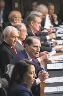  ?? J. Scott Applewhite / Associated Press ?? Sen. Ron Wyden, D-Ore. (center), the top Democrat on the Senate Finance Committee, criticizes the GOP tax plan.