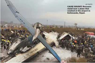  ?? AP PHOTO ?? CAUSE SOUGHT: Rescuers stand near a plane that crashed at the airport in Kathmandu, Nepal.