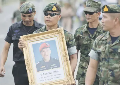  ?? Picture: Reuters ?? HE WILL BE REMEMBERED. An honour guard hold up a picture of Samarn Kunan, 38, a former member of Thailand’s elite navy Seal unit who died during the rescue operation.