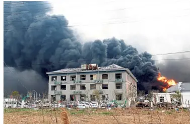  ??  ?? Raging blaze:A fire burning at the explosion site, while firefighte­rs (below) continue tehir work as smoke rises behind at Tianjiayi Chemical in Yancheng city, Jiangsu province. — AP/Reuters