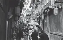  ?? PHOTOS BY YANG FEIYUE / CHINA DAILY ?? Left: Travelers walk in a street in Heping town, Fujian province. Right: A glimpse of the ancient town’s entrance.