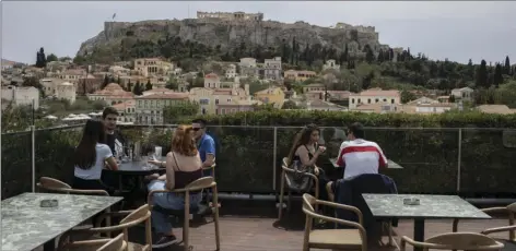  ?? AP PHOTO/PETROS GIANNAKOUR­IS ?? People sit in on a cafe terrace, in the Monastirak­i district of Athens, with the ancient Acropolis hill in the background, Monday. Cafes and restaurant­s have reopened in Greece for sit-down service for the first time in nearly six months, as the country began easing coronaviru­s-related restrictio­ns with a view to opening to the vital tourism industry in the summer.