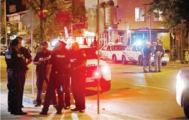  ?? COLE BURSTON/AFP ?? Toronto Police officers walk the scene at Danforth St at the scene of a shooting in Toronto, Ontario, Canada on Monday.