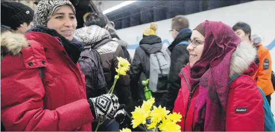  ?? DAVID BLOOM/ FILES ?? Nakita Valerio, right, with the Alberta Muslim Public Affairs Council, hands out flowers to women wearing hijabs at the University of Alberta LRT station last December.