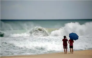  ?? —AFP ?? Two men watch the waves during swells brought by the typhoon Maysak on the Haeundae beach in Busan, as it headed towards the Korean Peninsula, on Wednesday.