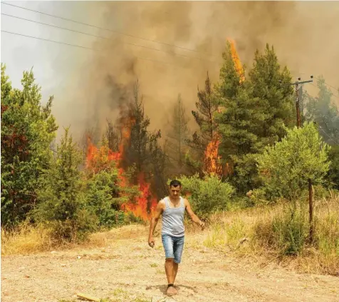 ?? Foto: Petros Karadjias/AP, dpa ?? Ein Mann bringt sich am Dienstag vor einem Waldbrand auf der griechisch­en Insel Euböa in Sicherheit.