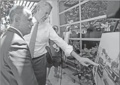  ?? Associated Press ?? New York City Mayor Bill de Blasio, right, points to a photo as Miami Beach Mayor Philip Levine, left, looks on during a tour Friday showing where the city has raised streets and installed pumps to combat rising tides in Miami Beach, Fla.