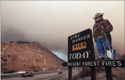  ?? Los Angeles Times/BRYAN CHAN ?? Smokey Bear looms over Interstate 5 in Southern California in September 2006 as smoke from a brush fire rises in Los Padres National Forest. His fire prevention campaign has resulted in fewer natural burns and more forestland packed with fuel for fires, some experts contend.