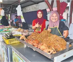  ??  ?? These traders smile for the camera as they await customers to come to their stall.