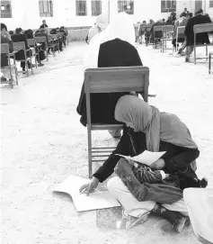  ?? AFP photo ?? This photo obtained from the Facebook account of Afghan professor Yahya Erfan shows Ahmadi sitting on the ground with her baby lon her lap as she takes an entrance exam for Nasir Khusraw private university. —