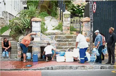  ?? — AFP ?? Bracing for hardship: Residents of poorer residentia­l areas collecting drinking water from pipes fed by an undergroun­d spring in St James, about 25km from the city centre in Cape Town.
