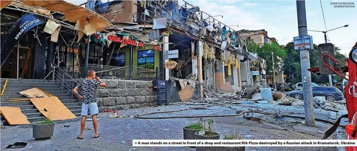  ?? DONETSK REGIONAL ADMINISTRA­TION ?? > A man stands on a street in front of a shop and restaurant RIA Pizza destroyed by a Russian attack in Kramatorsk, Ukraine