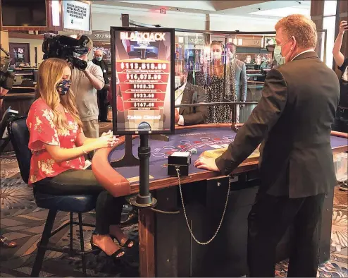  ?? Susan Haigh / Associated Press file photo ?? In this May 22, 2020, photo, a blackjack dealer at Foxwoods Resort Casino in Mashantuck­et demonstrat­es to reporters how new protective measures, including plastic shields, would work when the tribal-owned Foxwoods and neighborin­g Mohegan Sun expected to partially reopen on June 1, 2020.