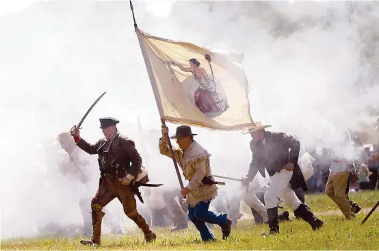  ?? Karen Warren / Houston Chronicle ?? TOP: Re-enactors playing the parts of members of the Texian Army charge toward the Mexican encampment during the Battle of San Jacinto on the grounds of the San Jacinto Battlegrou­nd.