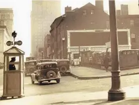  ?? BALTIMORE SUN ?? In 1934, Baltimore police officers stood in the middle of traffic, often in open air cans and occasional­ly shaded by oversized umbrellas. They hand turned signs, called semaphores, that said “Stop” and “Go.”