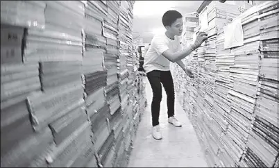  ?? KRIZJOHN ROSALES ?? A student arranges textbooks to be distribute­d in the coming school year at Taguig National High School.