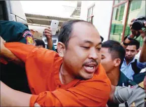  ?? HENG CHIVOAN ?? Political analyst Kim Sok is escorted into a police vehicle last year.