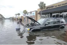  ?? JOHN BAZEMORE, AP ?? John Duke tends to his vehicle in Jacksonvil­le, Florida, which experience­d some of the state’s worst flooding.