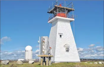  ?? KATHY JOHNSON PHOTO ?? A lighthouse at Baccaro Point has guided the way for mariners since 1851. The current structure was built in 1934 to replace the original lighthouse that was destroyed by fire. In the background is the last radar tower from what once was CFS Barrington. The radar tower has been operated as an unmanned Canadian Coastal Radar station under NORAD since the early 1990s.