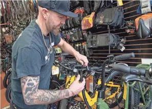  ?? ?? Jon Hughes, owner of the Downtown Ferndale Bike Shop, demonstrat­es disconnect­ing a cable to transform a class 2 e-bike into a class 1. Hughes also talks about the electric bikes he has for sale in his shop on Tuesday, as the Michigan DNR is proposing allowing class 1 and some class 2 e-bikes on unpaved trails in state parks.