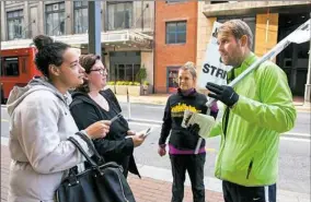 ?? Stephanie Strasburg/Post-Gazette ?? PSO cellists Bronwyn Banerdt, second from right, and Charlie Powers, right, of the Strip District, hold picket signs Monday as they talk to arts supporters Kim Webb, left, and Maria Shoop, both of Aspinwall, outside of Heinz Hall, Downtown.