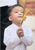  ??  ?? A two-year-old boy in Thai traditiona­l apparel holds a candle, lotus bud and three incense sticks as he walks around an ordination hall to commemorat­e Visakha Bucha Day.