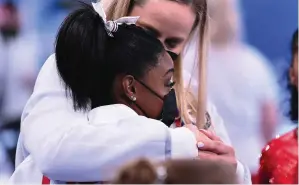  ??  ?? ABOVE Gymnast Simone Biles is consoled by her trainer after withdrawin­g from competitio­n in the 2020 Olympics