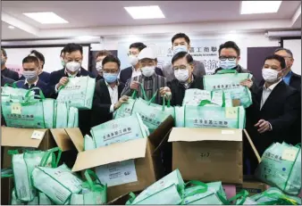  ?? CALVIN NG / CHINA DAILY ?? Members of the Hong Kong Commerce and Industry Associatio­ns gather at the associatio­n’s office in Kwun Tong on Friday, with 63,000 face masks ready to be distribute­d to the elderly.