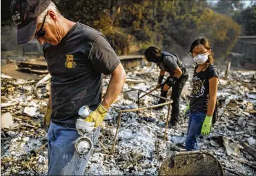  ?? MARCUS YAM / LOS ANGELES TIMES ?? From left: Jeff Lipscomb, Gabriel Lipscomb, 17, and Rachel Lipscomb, 11, look for items to recover in the wreckage of their burned home on Wednesday in Ventura, Calif., where a major blaze started on Dec. 4.