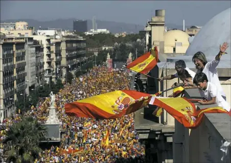  ??  ?? People on a rooftop wave Spanish flags Sunday during a march in downtown Barcelona, Spain, to protest the Catalan government’s push for secession from the rest of Spain.