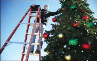  ?? HANNAH BUTLER/CONTRIBUTI­NG PHOTOGRAPH­ER ?? Ken Lederman, deputy fire marshal for the Russellvil­le Fire Department, fluffed the city’s Christmas tree during its setup on Monday. The Christmas tree stands near Russellvil­le’s Train Depot Park and will be officially lit during the Holiday Glow on Friday.