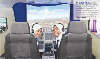  ?? – BERNAMAPIX ?? ON CLOUD NINE ... Year Six students of Gong Nangka primary school in Marang, Terengganu, Atiqah Yasmin Zuyawi (left) and Nur Alya Damia Muhammad at the controls of a flight simulator made by their school’s aeronautic­al club using recycled and used items.