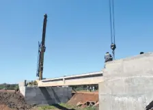  ??  ?? Las vigas de 30 toneladas se colocan sobre la estructura para el puente de la nueva carretera.