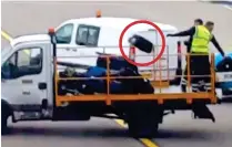  ??  ?? Up in the air: Handlers chuck a bag onto truck