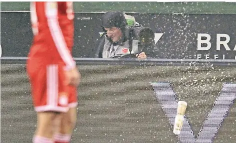  ?? FOTO: IMAGO ?? Als Fotograf gilt: Kapuze auf und ducken. Ein Bierbecher fliegt im Borussia-Park beim Spiel Mönchengla­dbach gegen München von den Rängen.