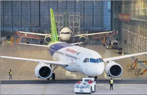  ?? YIN LIQIN / CHINA NEWS SERVICE ?? Workers move a C919, China’s first homegrown large passenger aircraft, out of a hangar at the Shanghai base of Commercial Aircraft Corp of China on Nov 8.