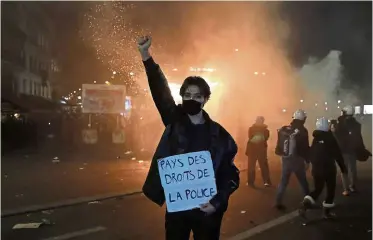  ??  ?? Not backing down: A protester holding a poster that reads ‘Land of rights for the police’ during the demonstrat­ion against a security law in Paris. — AP