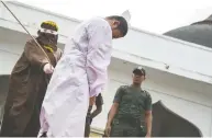  ?? CHAIDEER MAHYUDDIN / AFP / GETTY IMAGES / FILES ?? An Acehnese man convicted for “immoral acts” is lashed by a hooded local government officer during a public caning in 2015 in Banda Aceh.