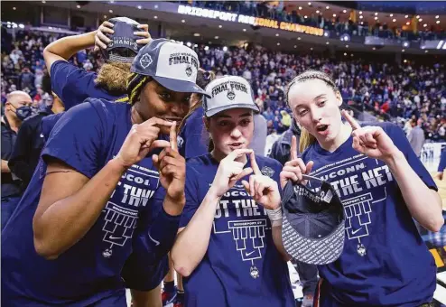  ?? M. Anthony Nesmith / Icon Sportswire via Getty Images ?? UConn’s Aaliyah Edwards, Nika Muhl and Paige Bueckers celebrate after defeating NC State 91-87 in double overtime at Total Mortgage Arena in Bridgeport on March 28.