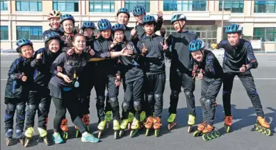  ??  ?? Zhang (fifth from left) and 13 members of the Special Olympics short-track speedskati­ng team in Qitaihe.