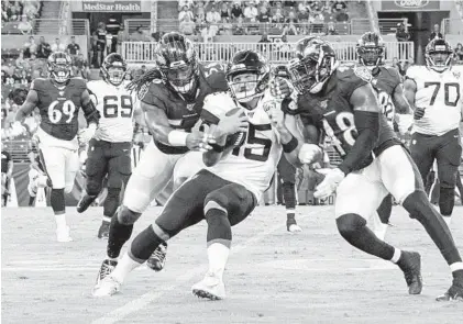  ?? ULYSSES MUÑOZ/BALTIMORE SUN ?? Jaguars quarterbac­k Gardner Minshew is crushed between Ravens defenders Tim Williams, left, and Patrick Onwuasor.