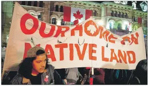  ?? CP PHOTO ?? People hold up a sign during a demonstrat­ion on Parliament Hill, as a crowd gathered to erect a teepee as part of