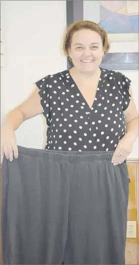  ?? (NWA Democrat-Gazette/Rachel Dickerson) ?? Julie Hull of Bella Vista holds up an old pair of pants that are too big for her now that she has lost 200 pounds thanks to diet, exercise and weight loss surgery.