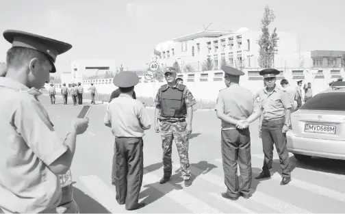  ??  ?? PARA pegawai polis Kyrgyz mengadakan sekatan jalan raya tidak jauh dari Kedutaan China di Bishkek, semalam.