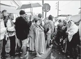  ??  ?? Tijuana, Baja California, hacen fila bajo la lluvia para recibir su ración de comida. Foto Afp