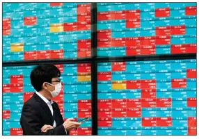  ?? (AP/Eugene Hoshiko) ?? A man checks out stock data for Japan’s Nikkei 225 index on an electronic board at a securities firm Friday in Tokyo.