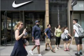  ?? MARK LENNIHAN — THE ASSOCIATED PRESS ?? People pass a Nike store in New York, Tuesday. An endorsemen­t deal between Nike and Colin Kaepernick is prompting a flood of debate online as sports fans react to the apparel giant backing an athlete known mainly for starting a wave of protests among NFL players of police brutality, racial inequality and other social issues.